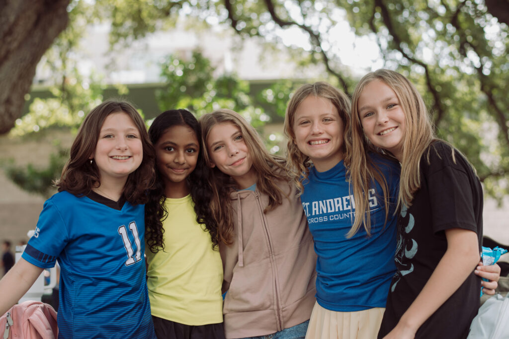 St. Andrew's Middle School students stand together with their arms around each other and smile.