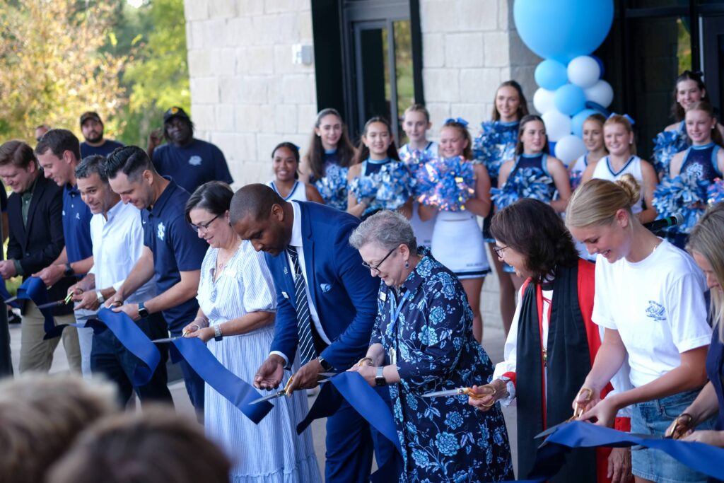 Members of the St. Andrew's community hold and cut a blue ribbon.