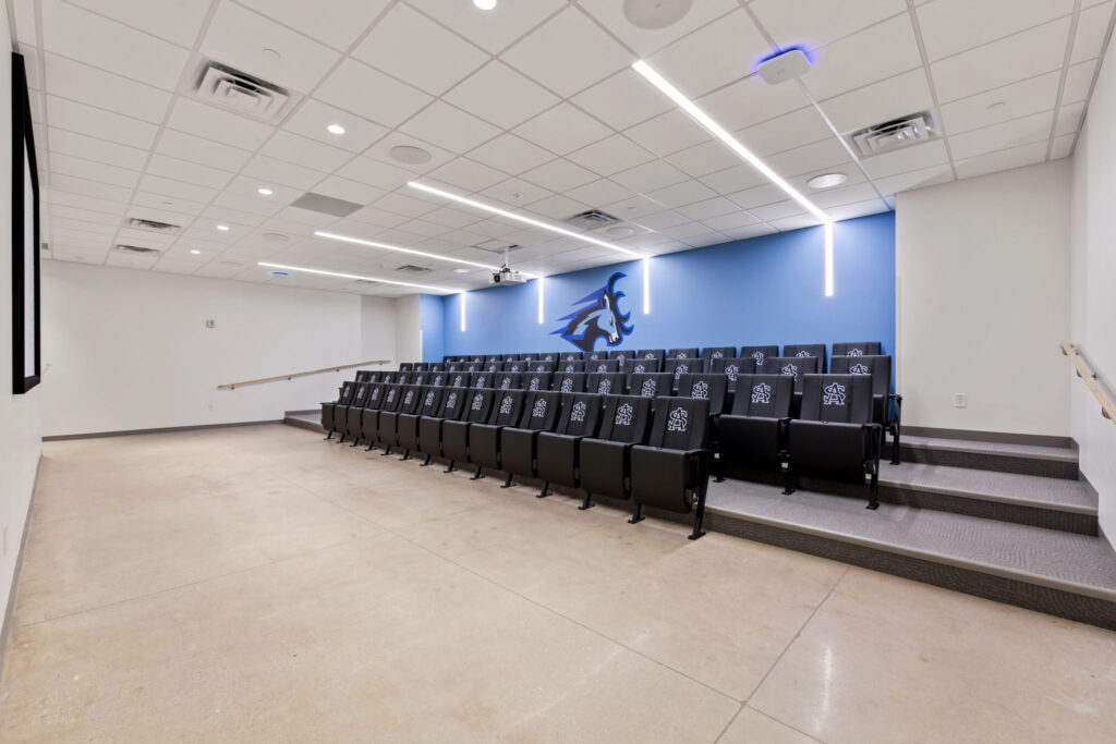 Photo of SAS film room seats. There is a blue Highlandr logo on the wall behind the seats.