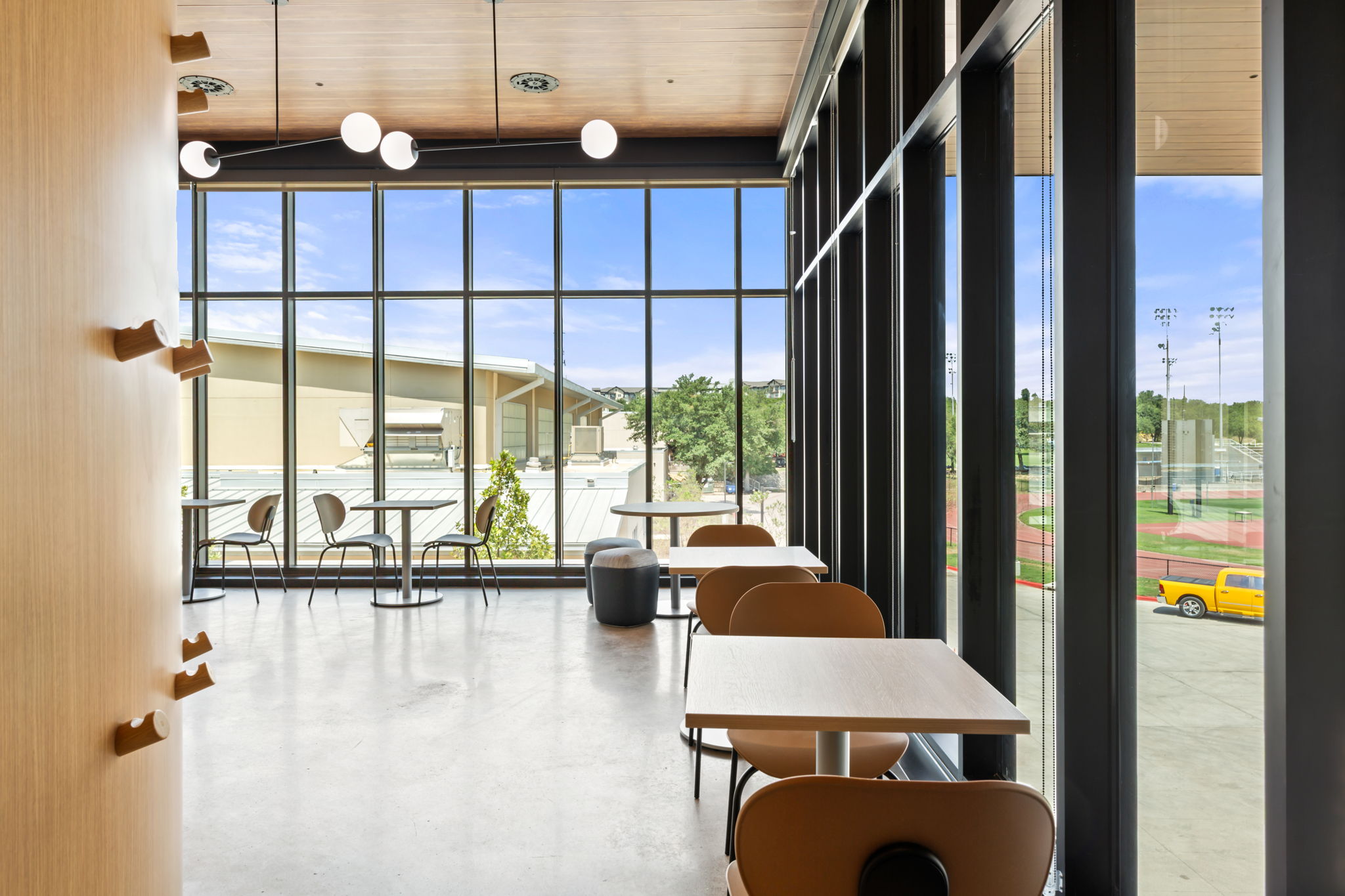 Student union second floor lounge. Tables and chairs line floor to ceiling windows.